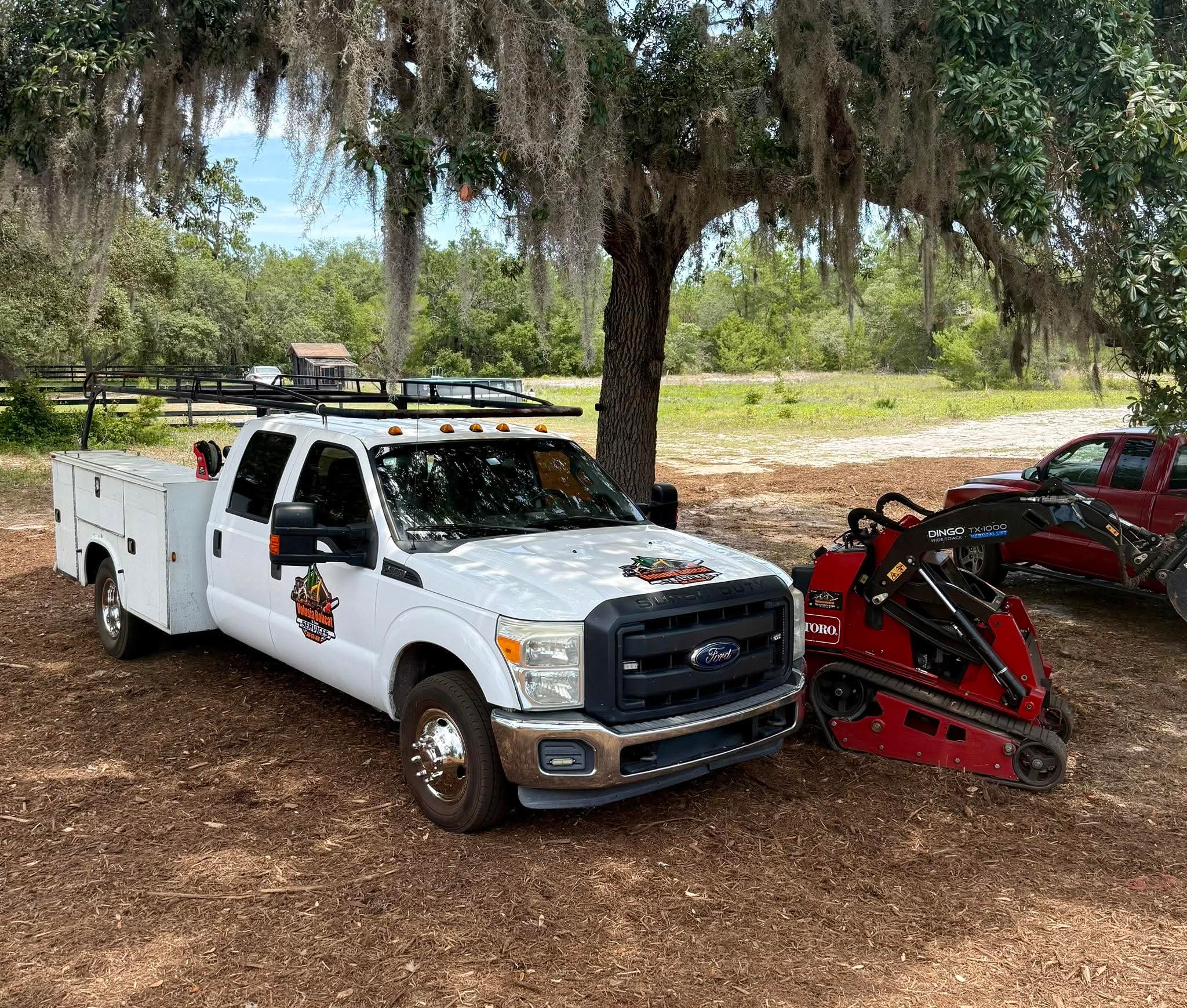 A white pickup truck with the Volusia Bobcat & Tree Service logo is parked in front of a house.